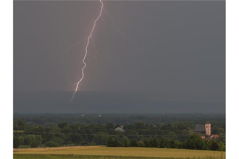 Vor einigen Tagen: Ein Blitz leuchtet hinter einem Stadtteil von Hanau. Foto: Sebastian Gollnow/dpa