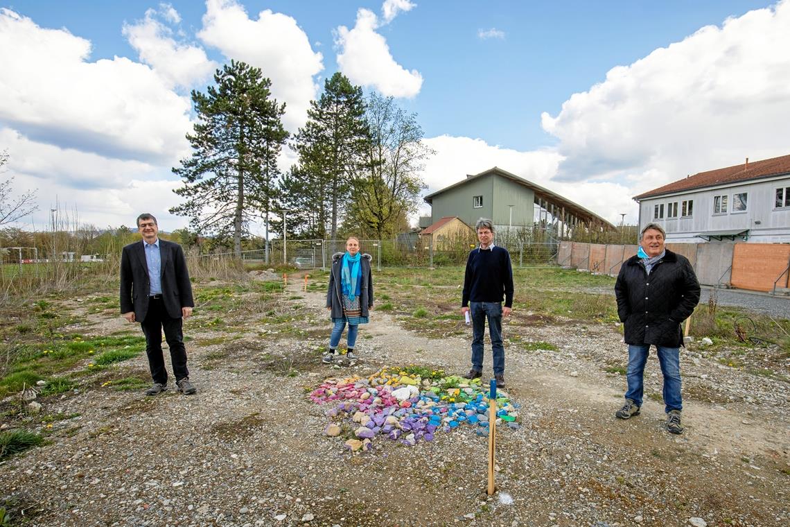 Vorfreude auf den Baustart: (von links) Vorstand Heiko Höhle, Lehrerin Tatiana Onneken, Geschäftsführer Christoph Ernst und Bauleiter Rudi Altmeyer. Die bunten Steine haben Schülerinnen und Schüler bei der Übergabe des Baugrundstücks hier abgelegt.Foto: A. Becher