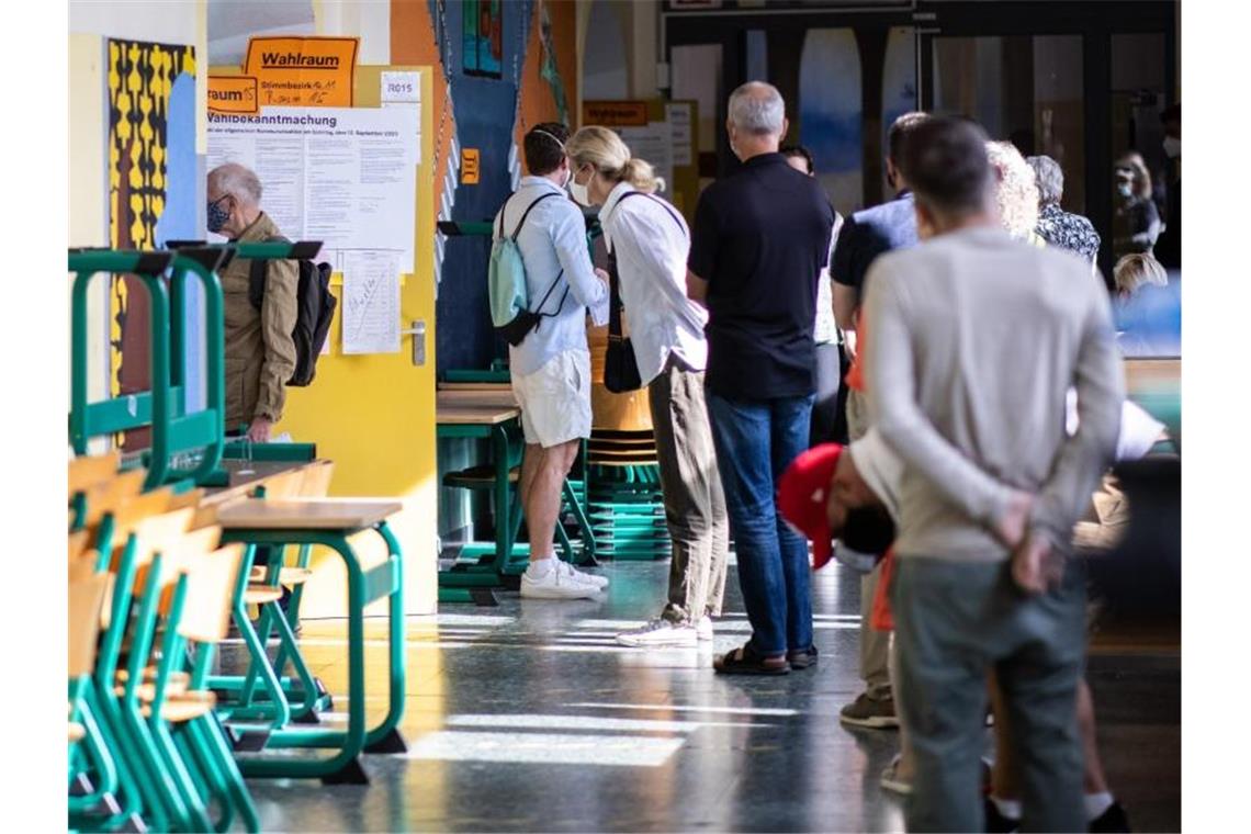 Wählerinnen und Wähler stehen zur Stimmabgabe in Düsseldorf an. Wählen darf, wer in NRW wohnt, die deutsche Staatsangehörigkeit oder die eines anderen EU-Landes besitzt. Das Mindestalter beträgt 16 Jahre. Foto: Marcel Kusch/dpa