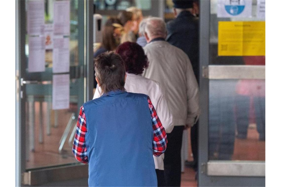 Wählerinnen und Wähler warten darauf, in einem Wahllokal ihre Stimmen abzugeben. Foto: Stefan Sauer/dpa