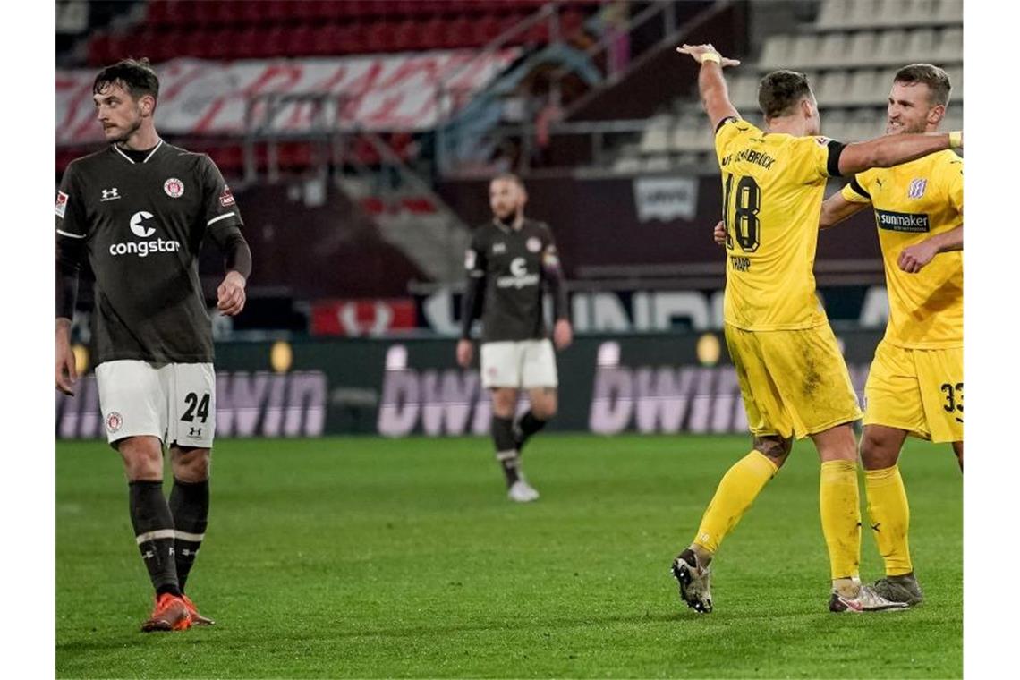 Während die Spieler vom VfL Osnabrück (r) ihren Sieg feiern schiebt der FC St. Pauli (l) Frust. Foto: Axel Heimken/dpa