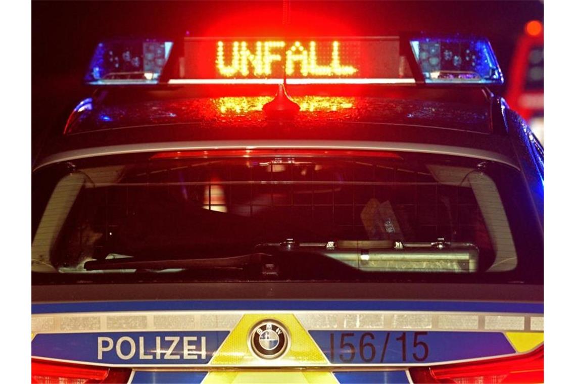 Während einer Unfallaufnahme spiegelt sich das Blaulicht und der LED- Schriftzug "Unfall" auf dem nassen Dach eines Polizestreifenwagens. Foto: Stefan Puchner/Archivbild