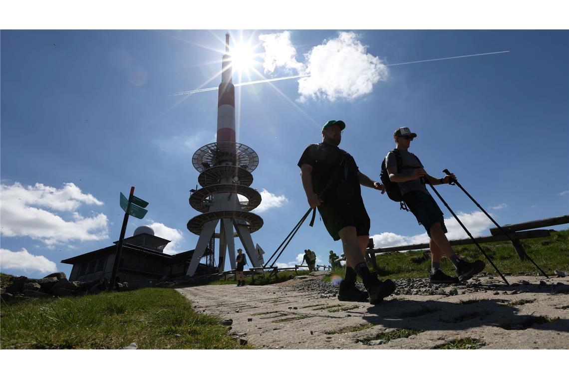 Wanderer gehen bei strahlendem Sonnenschein über einen Weg auf dem Brocken, im Hintergrund steht der Fernmeldeturm.