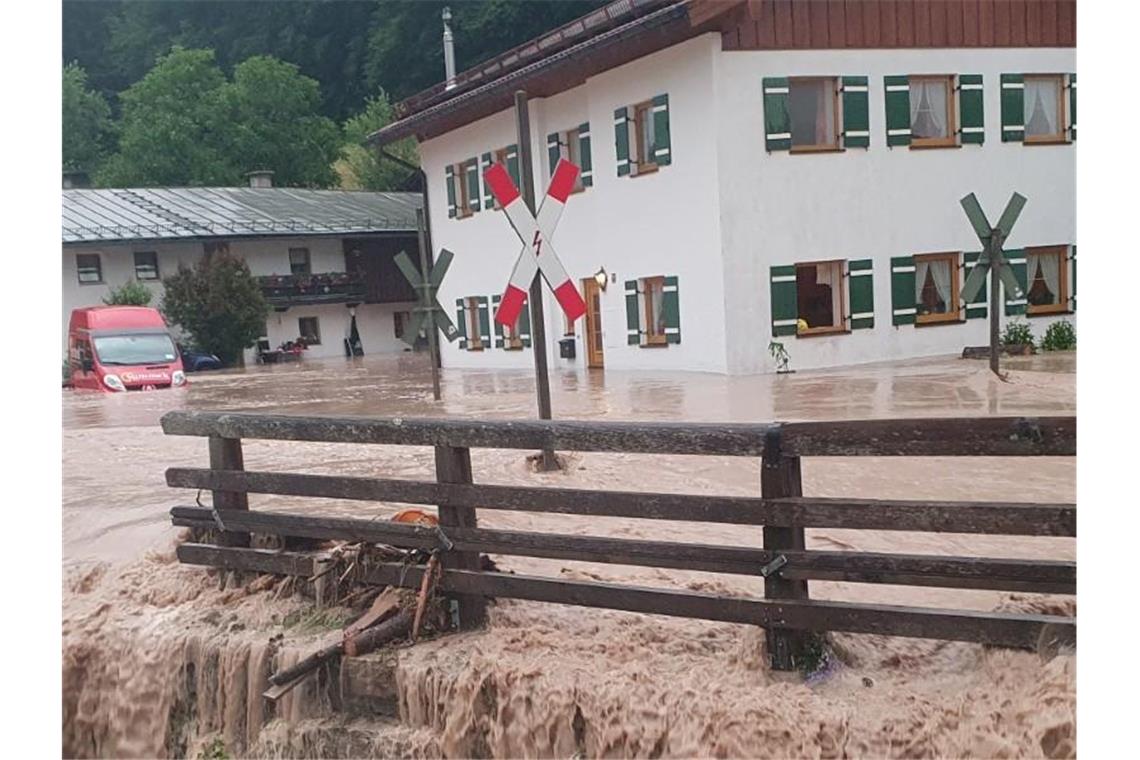 Wasser fließt über einen Platz vor einem Haus. Der Landkreis Berchtesgadener Land hat nach starkem Regen wegen Hochwassers den Katastrophenfall ausgerufen. Foto: Kilian Pfeiffer/dpa