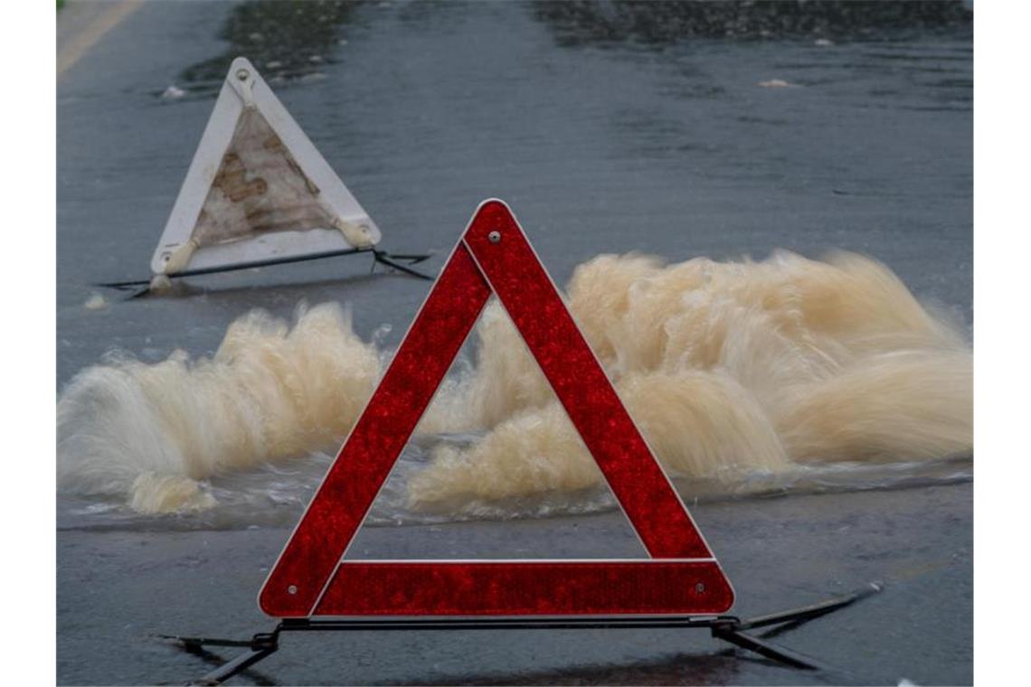 Wasser sprudelt aus einem Kanal einer teils gesperrten Fahrbahn. Foto: Harald Tittel/dpa