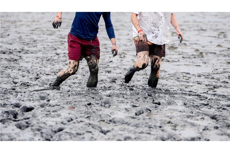 Watt en Schlick Festival - Zwei Teilnehmer gehen bei den deutschen Meisterschaften im Schlickrutschen im Rahmen des Watt en Schlick Fest am Strand von Dangast durch das Watt.
