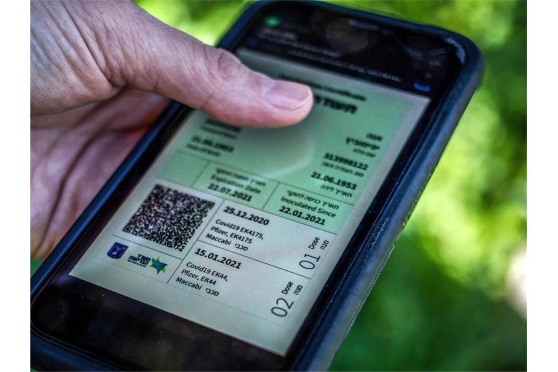 Weg zur Freiheit: Ein israelischer Mann hält ein Smartphone in der Hand, auf dem der sogenannte grüne Pass abgebildet ist. Foto: Ilia Yefimovich/dpa