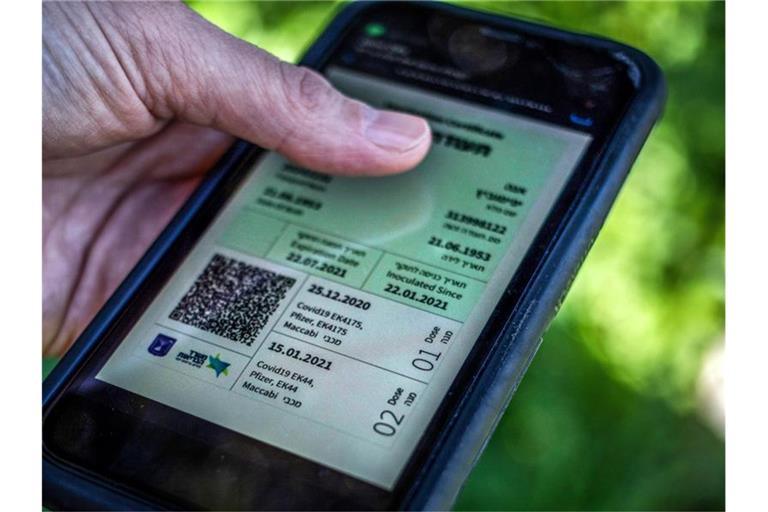 Weg zur Freiheit: Ein israelischer Mann hält ein Smartphone in der Hand, auf dem der sogenannte grüne Pass abgebildet ist. Foto: Ilia Yefimovich/dpa