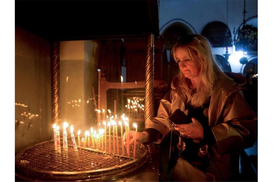 Christen in aller Welt feiern Weihnachten Weihnachten in Bethlehem: Eine Besucherin zündet eine Kerze in der Geburtskirche an. Foto: Majdi Mohammed/AP/dpa