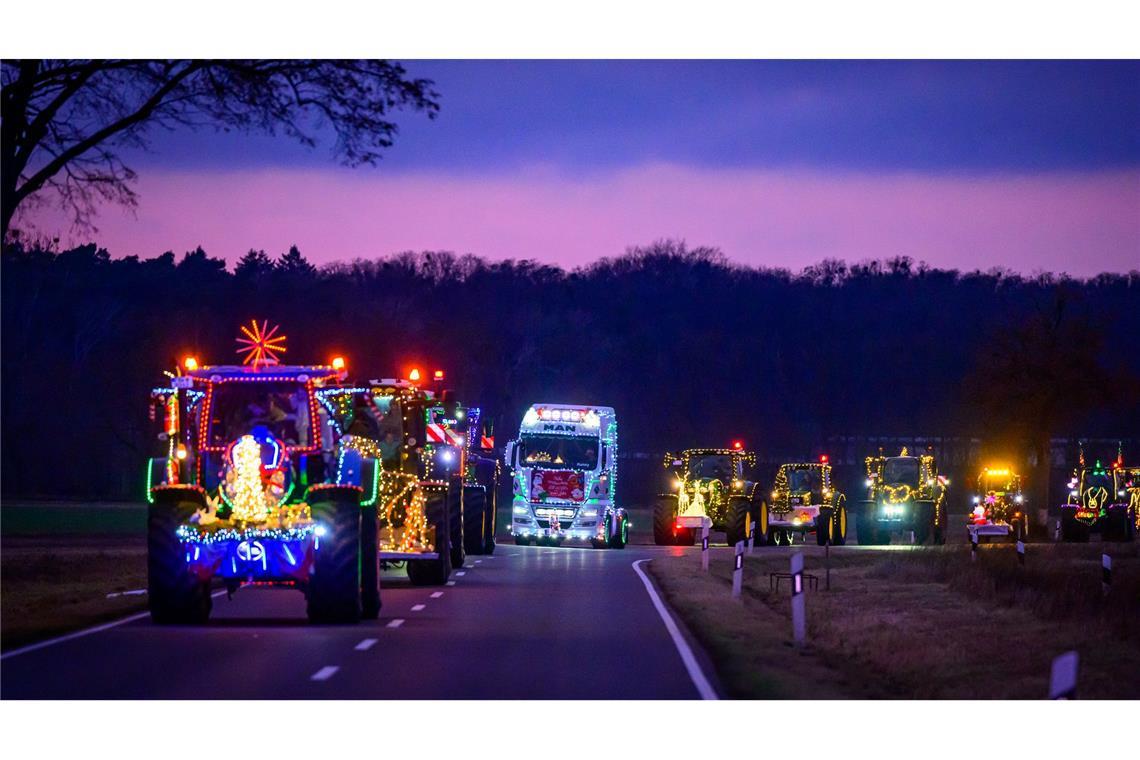 Weihnachtlich beleuchtete und geschmückte Traktoren und Lkw sind bei der Lichterfahrt der Oderlandbauern in Brandenburg unterwegs.