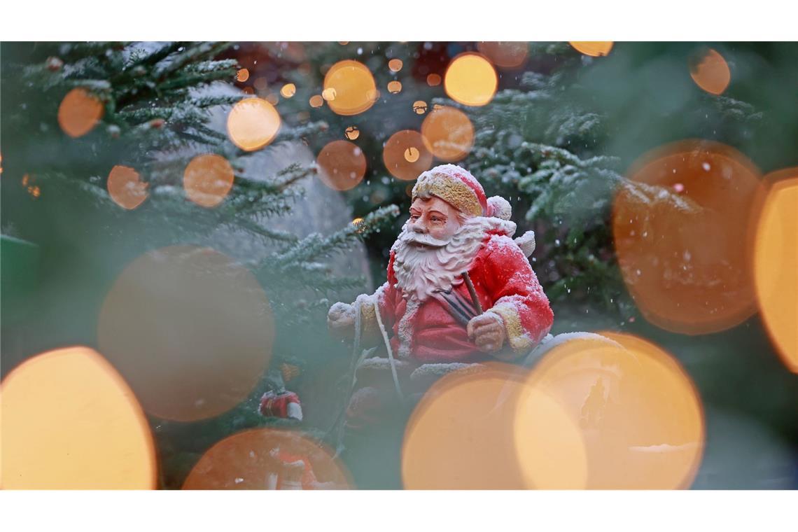Bilder des Tages Weihnachtliches in Sachsen-Anhalt: Blick durch eine Lichterkette auf eine schneebedeckte Weihnachtsmannfigur.