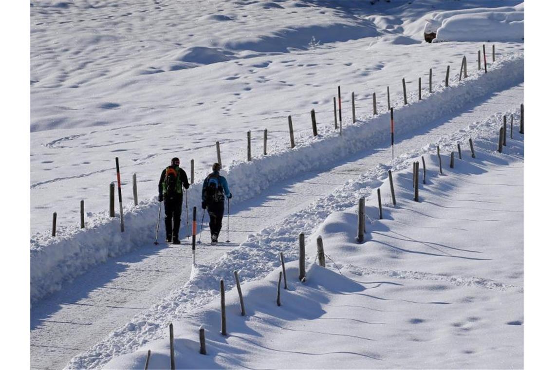 Weiße Pracht: Wanderer gehen bei Sonnenschein durch eine schneebedeckte Landschaft im bayerischen Bad Hindelang. Foto: Karl-Josef Hildenbrand/dpa