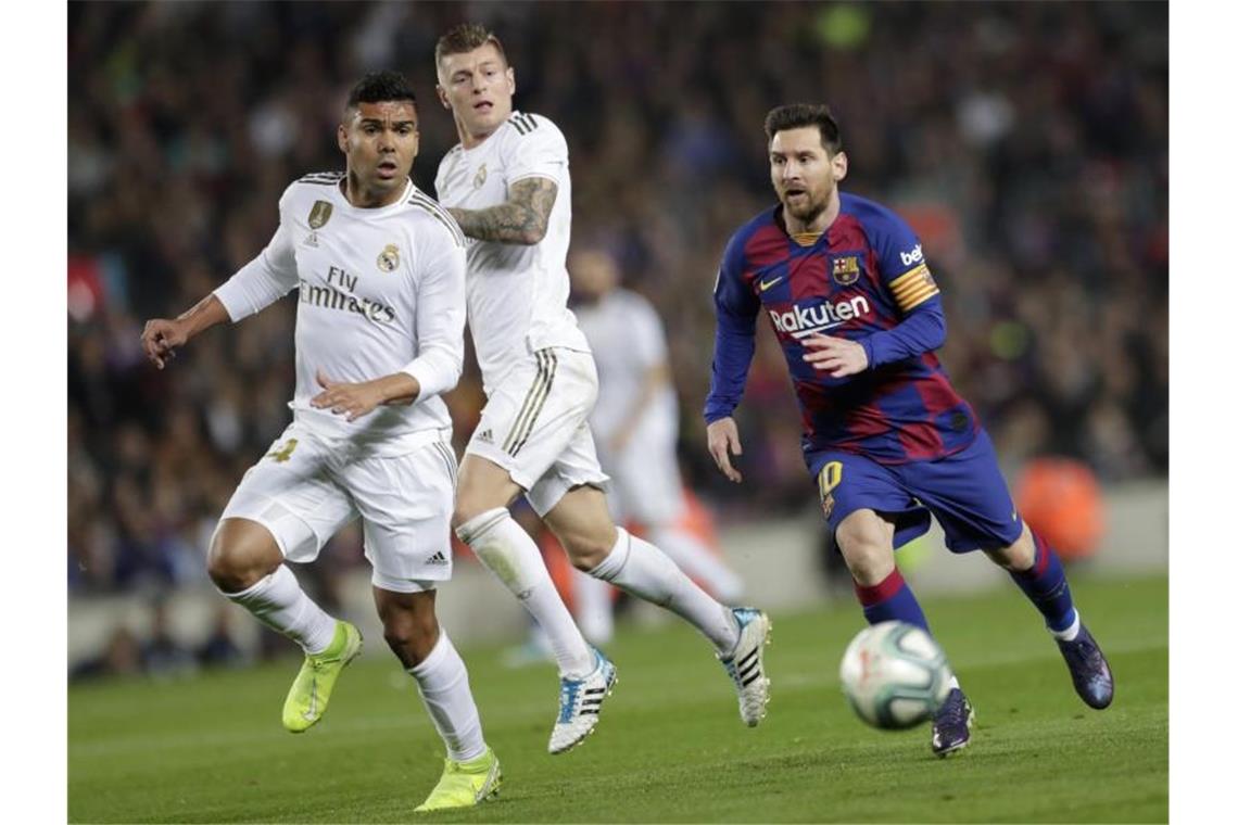 Weiße Überzahl: Barcas Lionel Messi (r) sieht sich Casemiro (l) und Toni Kroos gegenüber. Foto: Bernat Armangue/AP/dpa