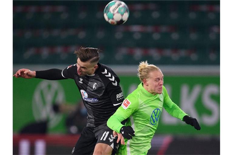 Wer kommt an den Ball? Freiburgs Ermedin Demirovic (l) und Wolfsburgs Xaver Schlager in Aktion. Foto: Swen Pförtner/dpa