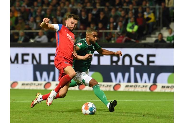 Werders Manuel Mbom (r) und Heidenheims Denis Thomalla kämpfen um den Ball. Foto: Carmen Jaspersen/dpa