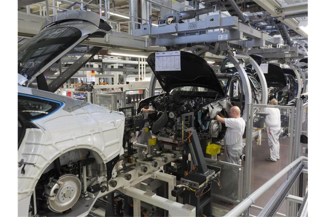 Werksmitarbeiter montieren in einer Produktionshalle von Audi bei der sogenannten „Hochzeit“ den Motor an einem A6. Foto: Ronald Wittek/dpa