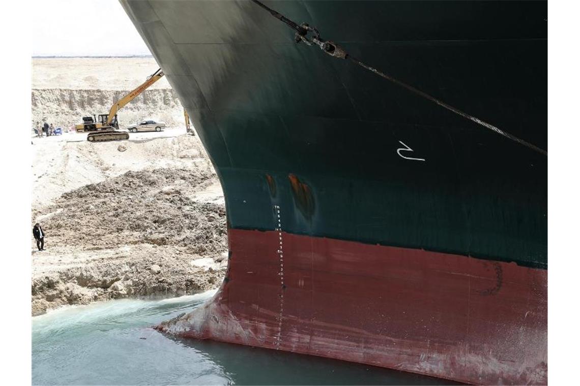 Unternehmen fürchten Folgen eines längeren Suezkanal-Staus Wie David neben Goliath: Ein Bagger (l) beteiligt sich an den Arbeiten zur Freisetzung der „Ever Given“. Foto: -/Suez Canal Authority/dpa