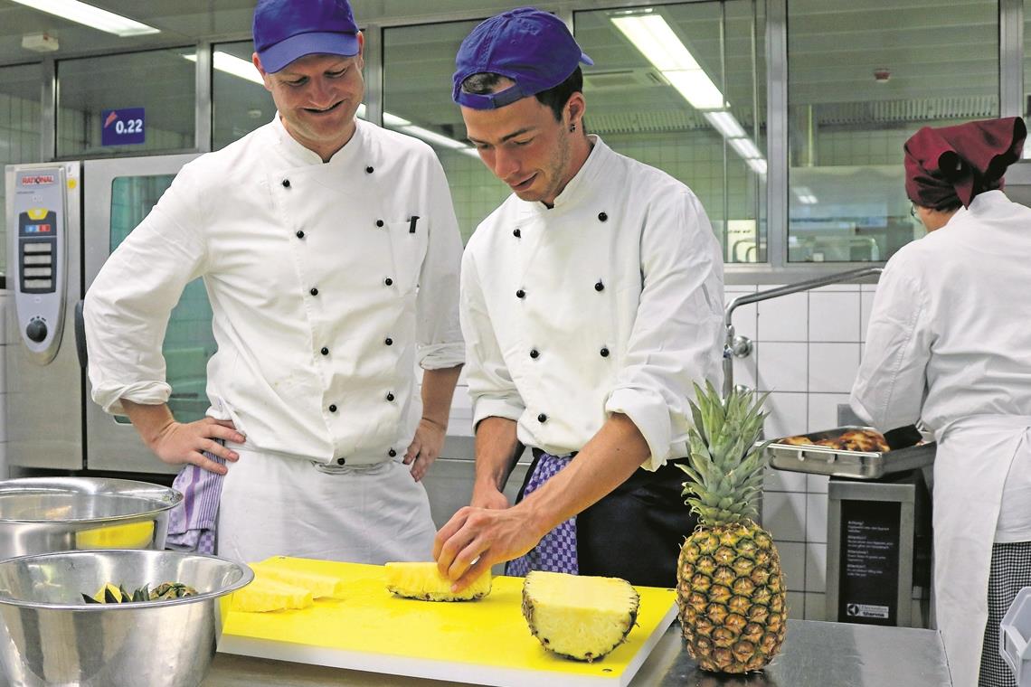 Luca Schüle startet mit seinem Küchenkönnen durch Wie schneidet man eine Ananas auf? Solche Handgriffe lernt man in der Ausbildung zum Fachpraktiker Küche. BBW-Ausbilder Holger Wahl schaut Luca Schüle dabei über die Schulter. Foto: privat