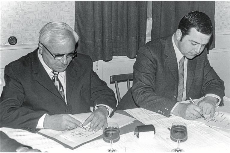 Wilhelm Schadt (links) und Egon Halter unterzeichnen den Vertrag, der die Entstehung von Weissach im Tal bedeutete. Foto: Archiv