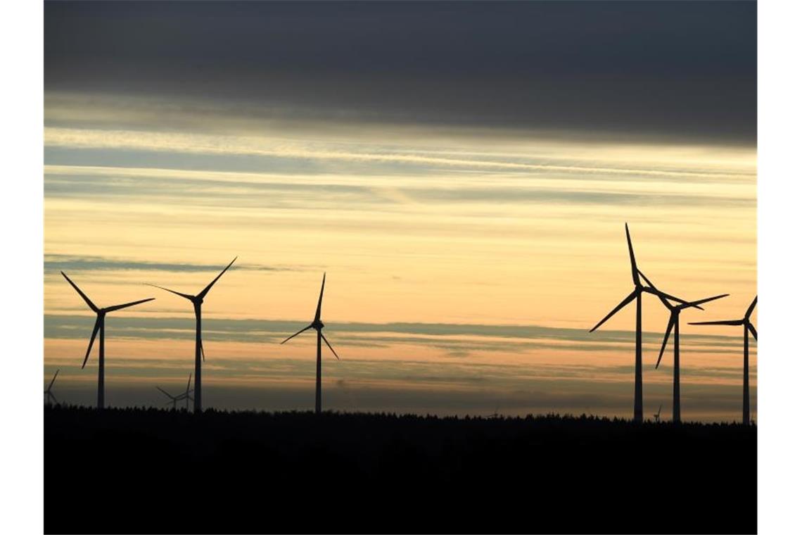 Windkraftanlagen stehen im Morgenlicht unter einem dunklen Wolkenstreifen. Foto: Carsten Rehder