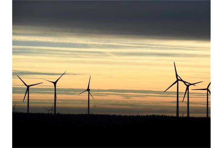 Windkraftanlagen stehen im Morgenlicht unter einem dunklen Wolkenstreifen. Foto: Carsten Rehder