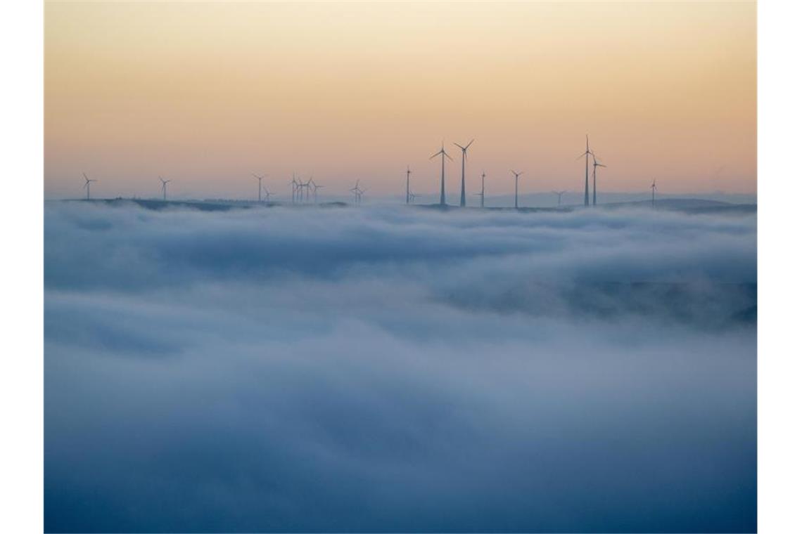Hoch „Kai“ bringt Sonne am Wochenende, aber es wird kalt Windkraftanlegen im Hochwald ragen am Morgen aus dem Nebel, unter dem die Stadt Trier noch im Verborgenen liegt. Foto: Harald Tittel/dpa
