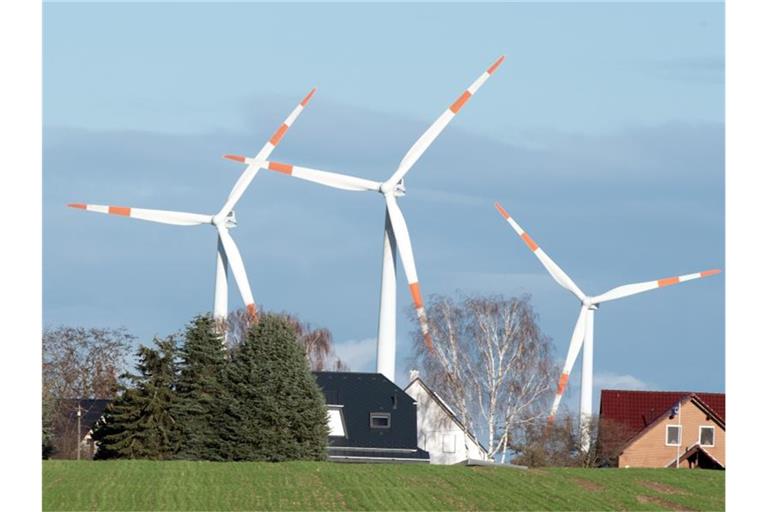 Windräder drehen sich hinter den Häusern von Krummensee im brandenburgischen Landkreis Barnim. Foto: Soeren Stache/zb/dpa