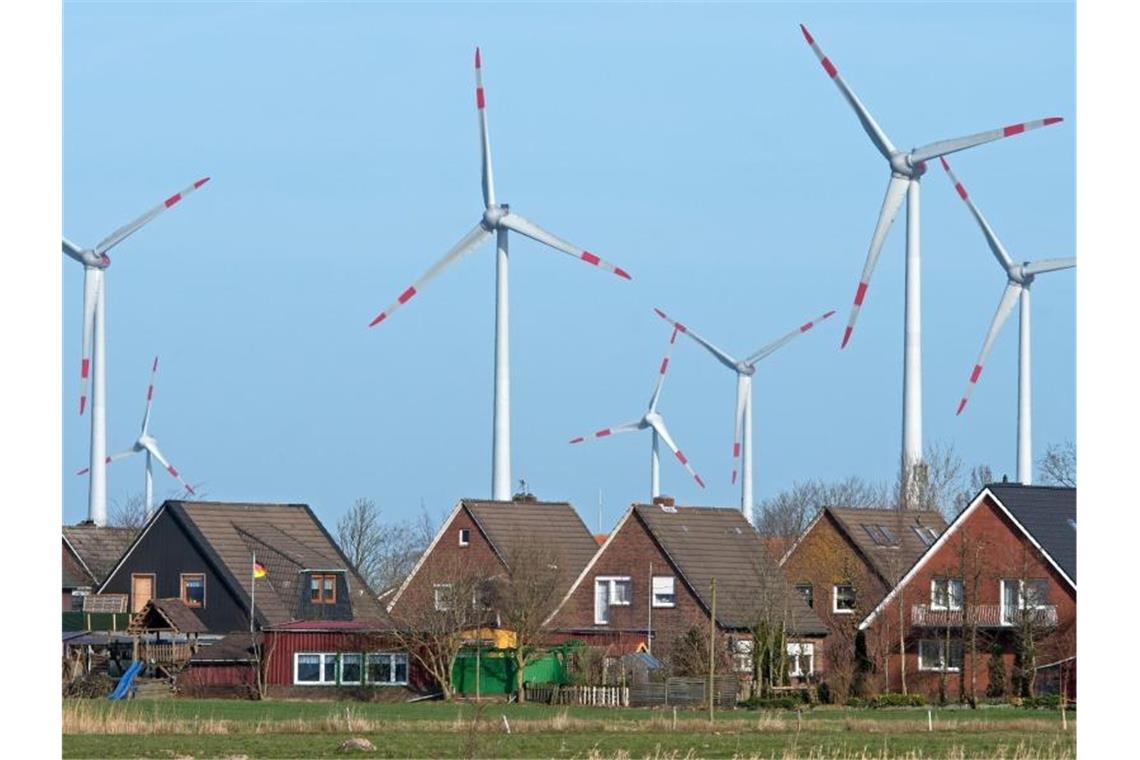 Windräder eines Windparks hinter einer Wohnsiedlung. Foto: Ingo Wagner/dpa