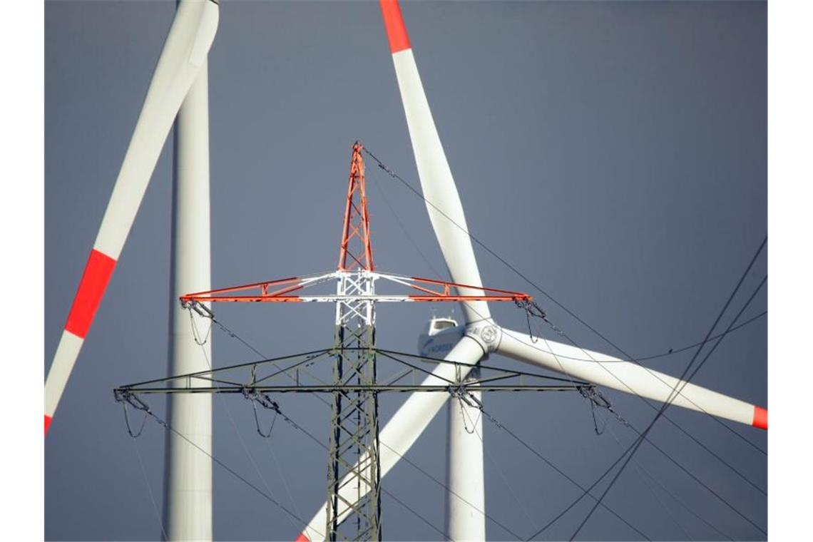 Windräder und ein Strommast stehen in Erkelenz. Die EEG-Umlage zur Förderung des Ökostroms wäre im nächsten Jahr auf ein Rekordhoch gestiegen - allerdings hat die Bundesregierung bereits eine Deckelung angekündigt. Foto: David Young/dpa