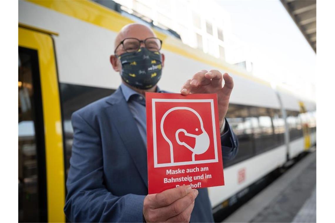Winfried Hermann (Bündnis 90/Die Grünen) hält eine Hinweistafel zur Maskenpflicht in der Hand. Foto: Sebastian Gollnow/dpa