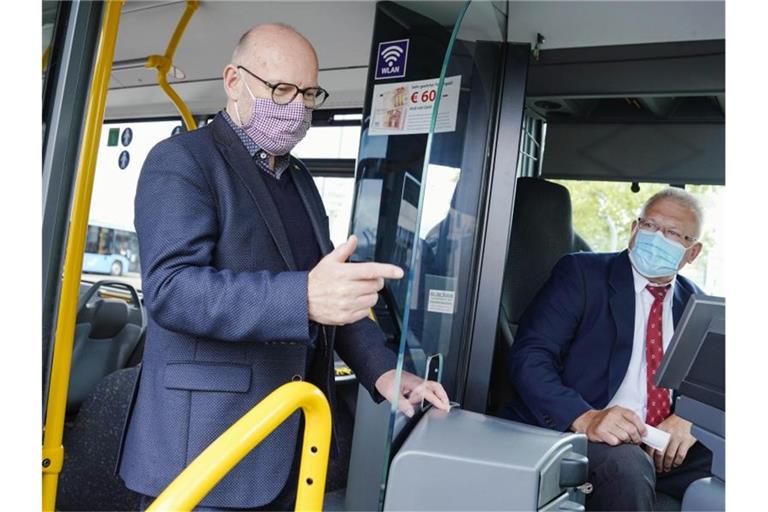 Winfried Hermann (Grüne) steht in einem Bus mit Schutzscheibe. Foto: Uwe Anspach/dpa/Archivbild