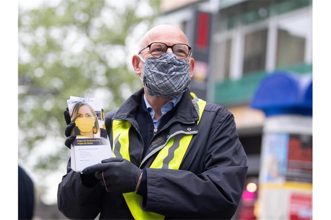 Winfried Hermann steht mit Flyern, die Mundschutz bewerben auf der Königstraße. Foto: Sebastian Gollnow/dpa/Archivbild