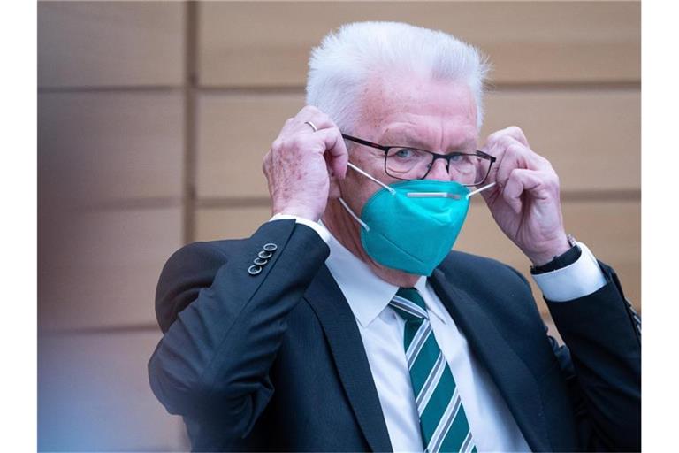 Winfried Kretschmann (Bündnis 90/Die Grünen), Ministerpräsident von Baden-Württemberg, zieht einen Mund-Nasenschutz auf. Foto: Sebastian Gollnow/dpa/Archivbild