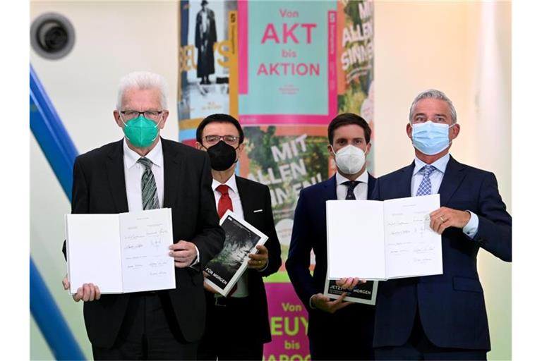Winfried Kretschmann (Die Grünen), Ministerpräsident von Baden-Württemberg, und Thomas Strobl (r, CDU), Landesvorsitzender der CDU Baden-Württemberg, halten in der Staatsgalerie nach der Unterzeichnung den Koalitionsvertrag der grün-schwarzen Landesregierung von Baden-Württemberg in den Händen. Foto: Bernd Weißbrod/dpa