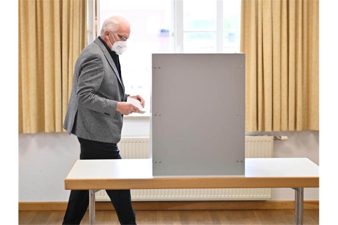Winfried Kretschmann geht zur Wahlkabine, um danach seinen Stimmzettel in die Wahlurne einzuwerfen. Foto: Felix Kästle/dpa