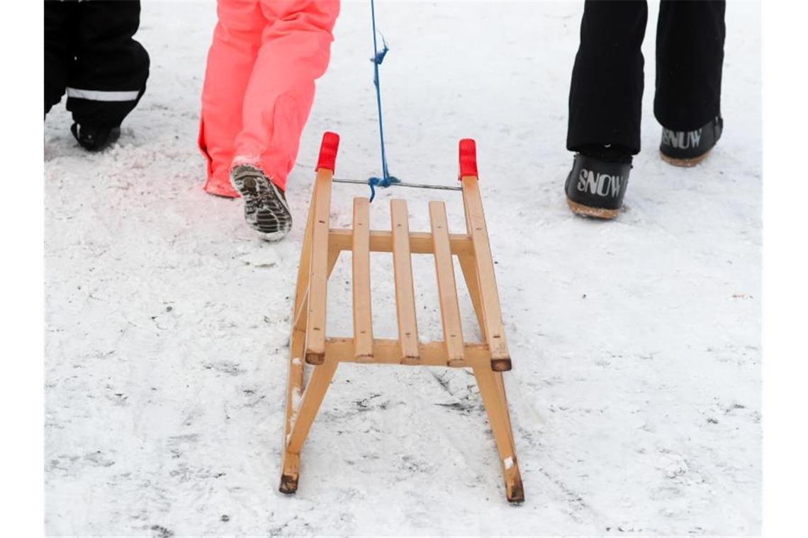 Winterurlauber gehen mit einem Schlitten zu einer Rodelbahn. NRW erwägt erneut eine Verlängerung der Winterferien. Foto: Jan Woitas/dpa-Zentralbild/ZB