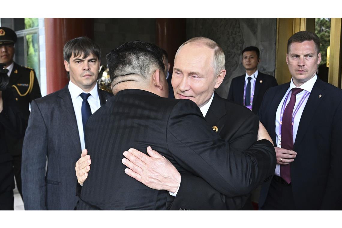 Putin antwortet Trump: Keine Verschwörung gegen die USA Wladimir Putin (M,r-l) und Kim Jong-un umarmen sich am Rande der Militärparade in Peking.