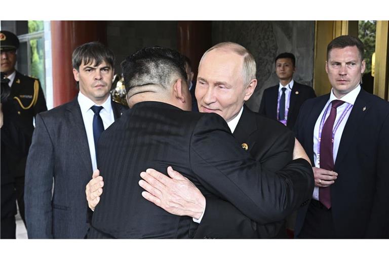 Wladimir Putin (M,r-l) und Kim Jong-un umarmen sich am Rande der Militärparade in Peking.