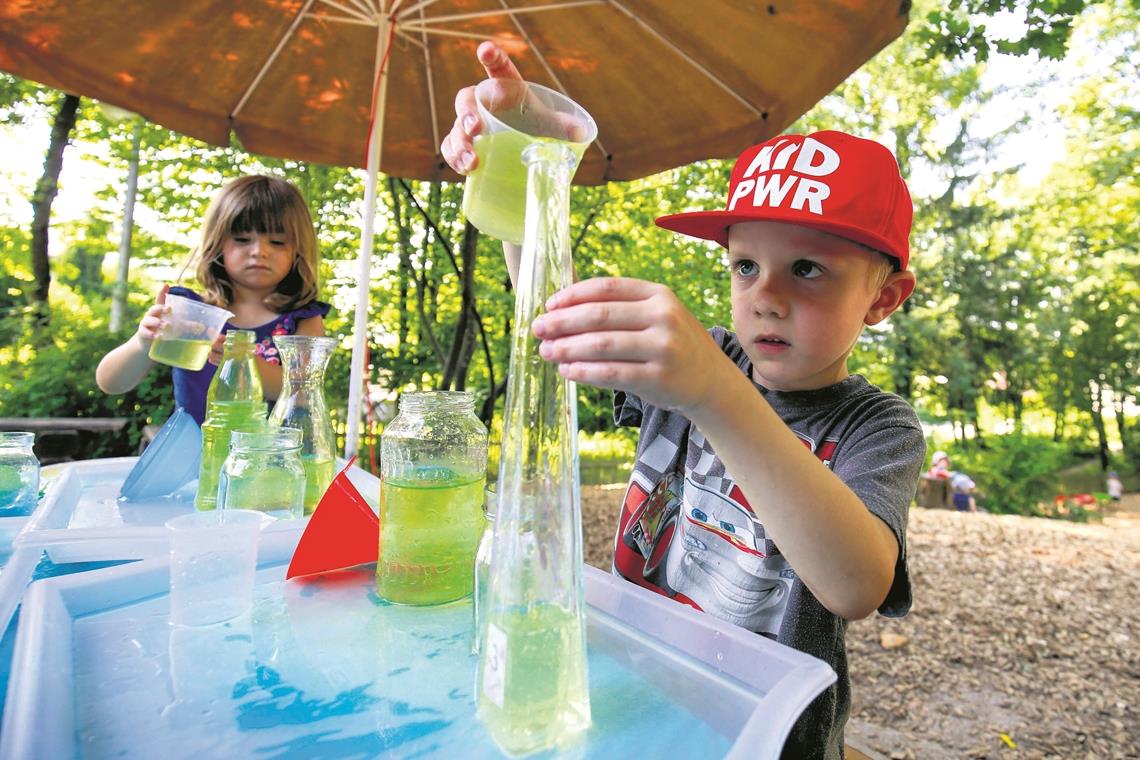 Wo passt mehr Wasser rein: In die schmale Flasche oder in das bauchige Marmeladenglas? Spielerisch lernen der sechsjährige Finjas und die dreijährige Lia im Kindergarten Am Sommerrain naturwissenschaftliche Zusammenhänge kennen. Foto: A. Becher