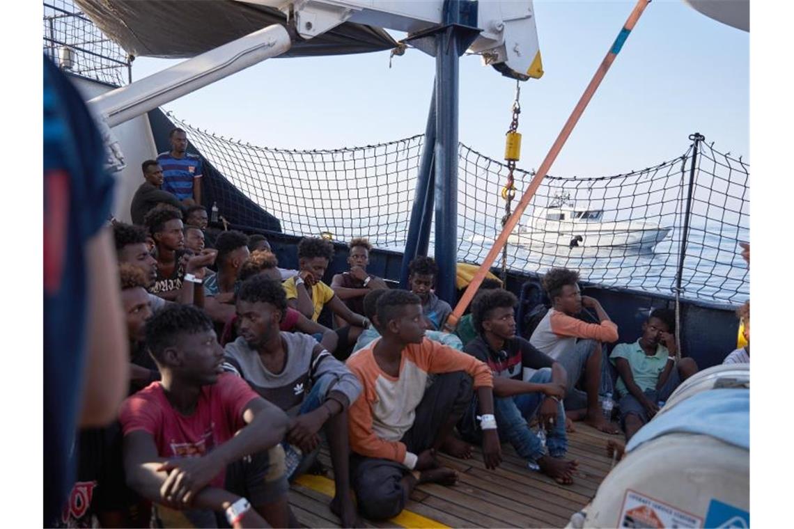 Wohin? Flüchtlinge an Bord des Seenotrettungsschiffs „Alan Kurdi“, während ein Boot der italienischen Guardia di Finanza vorbei fährt. Foto: Fabian Heinz/Sea-Eye