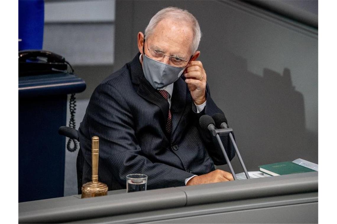 Wolfgang Schäuble (CDU), Bundestagspräsident, nimmt vor der Regierungsbefragung seine Maske ab. Foto: Michael Kappeler/dpa