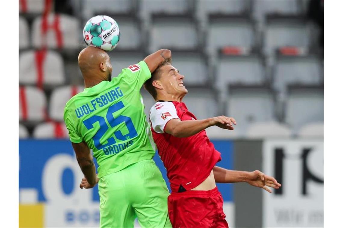 Wolfsburgs John Anthony Brooks (l) kommt vor Freiburgs Nils Petersen an den Ball. Foto: Tom Weller/dpa