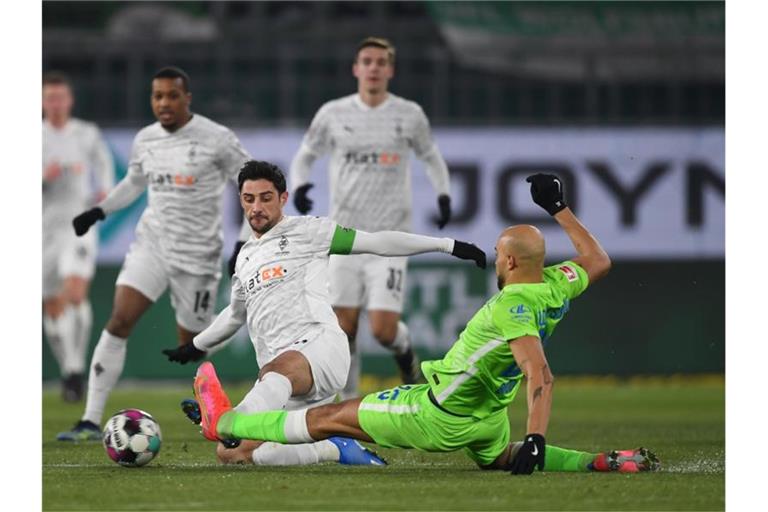Wolfsburgs John Brooks (r) und Gladbachs Lars Stindl teilten sich mit ihre Teams die Punkte. Foto: Swen Pförtner/dpa