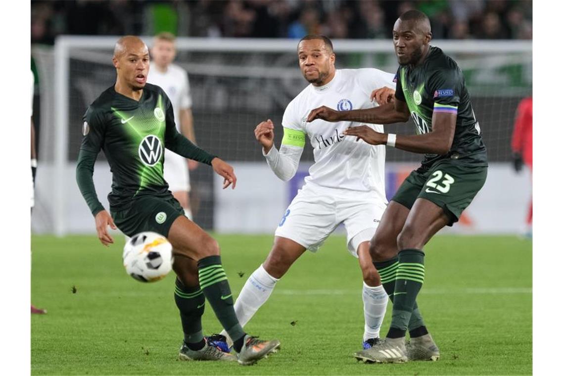 Wolfsburgs Marcel Tisserand (l) und Josuha Guilavogui (r) kämpfen mit Gents Vadis Odjidja um den Ball. Foto: Peter Steffen/dpa