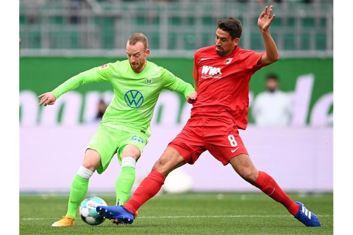 Wolfsburgs Maximilian Arnold (l) kämpft mit Augsburgs Rani Khedira um den Ball. Foto: Swen Pförtner/dpa