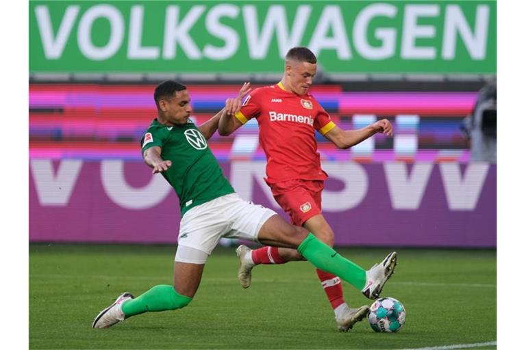 Wolfsburgs Neuzugang Maxence Lacroix (l) setzt gegen Leverkusens Talent Florian Wirtz zur Grätsche an. Foto: Peter Steffen/dpa