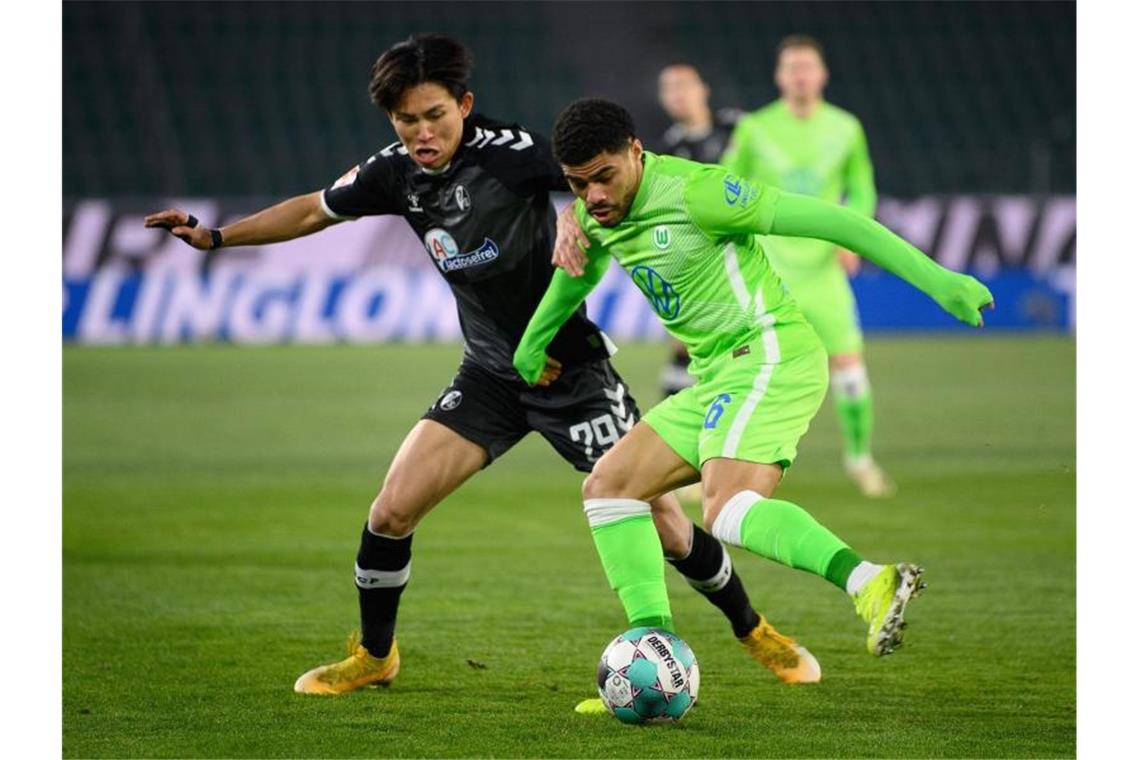 Wolfsburg mit 3:0-Sieg gegen Freiburg auf Platz drei Wolfsburgs Paulo Otávio (r) spielt gegen Freiburgs Wooyeong Jeong. Foto: Swen Pförtner/dpa