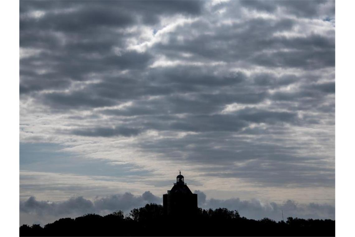 Wolken hängen über dem Leuchtturm auf Neuwerk. Foto: Daniel Bockwoldt/dpa