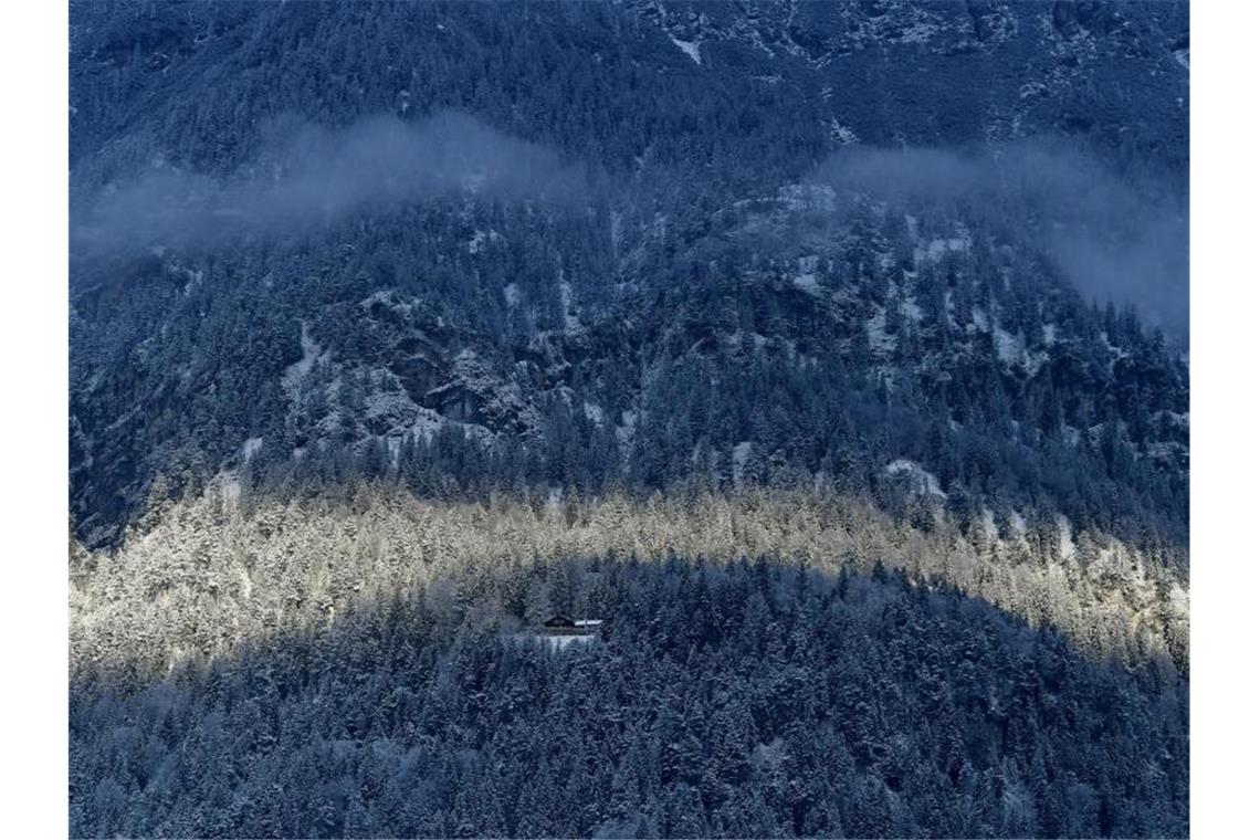 Ungemütliches Wetter am dritten Adventswochenende Wolken und Sonne formen einen Bogen an einem Berghang. Foto: Angelika Warmuth/dpa/Symbolbild