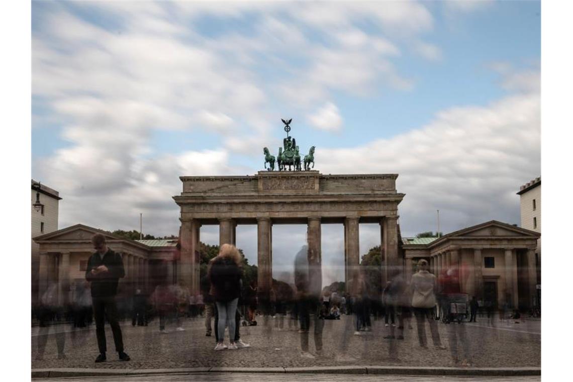 Wolken ziehen über das Brandenburger Tor, während zahlreiche Menschen auf dem Pariser Platz stehen. Foto: Paul Zinken/Archiv